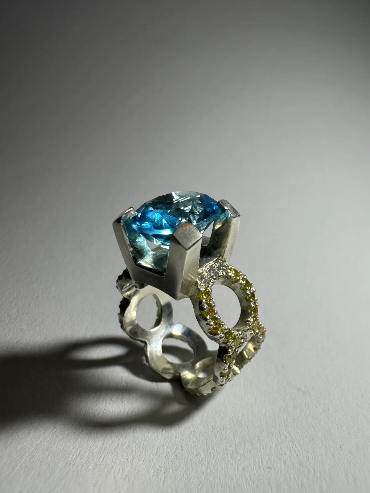 Silberring mit großem blauem Topas, die geschwungene Ringschiene mit gelben und weißen Moissaniten besetzt